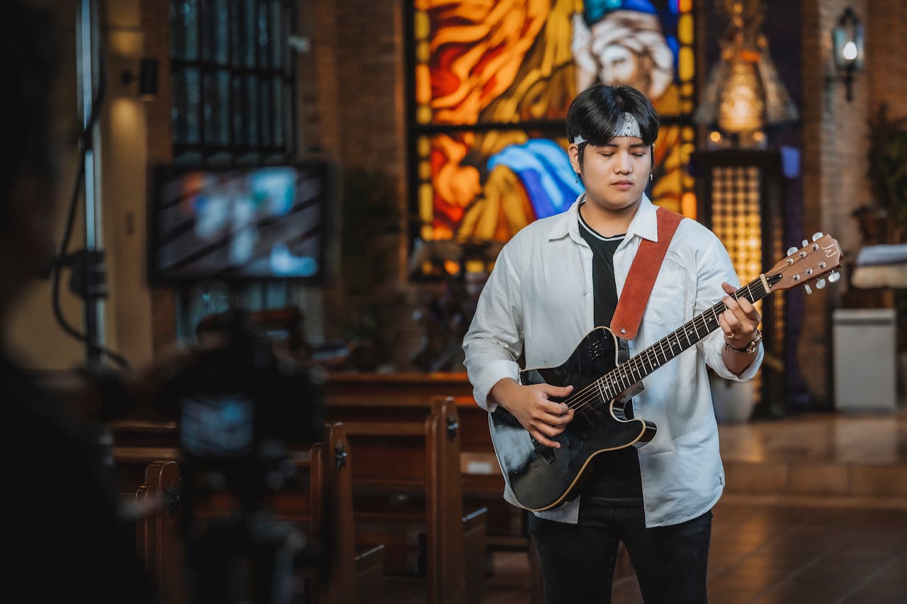 Young musician playing electric guitar during a recording session in a church.