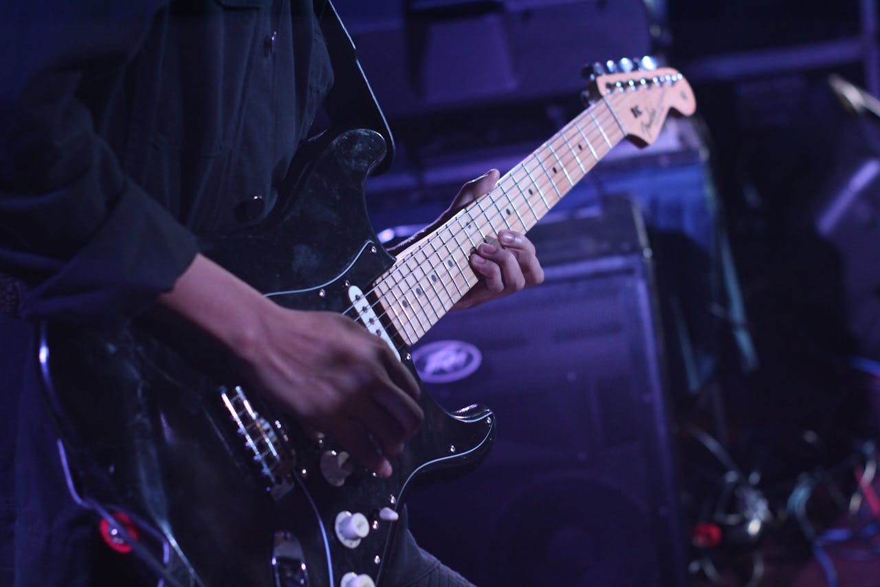 about-img Musician playing an electric guitar on stage during a live performance.