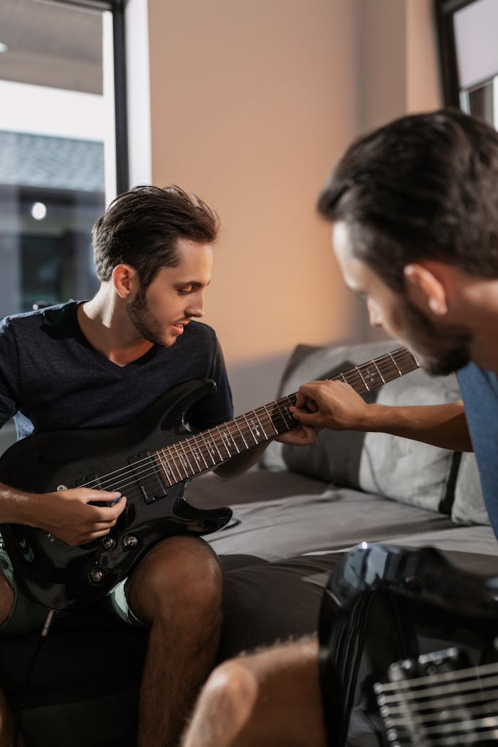 Two brothers learning to play electric guitar together in a cozy indoor setting, bonding over music.