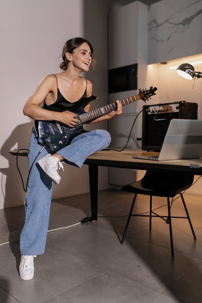 Mastering the First Impression: Your intriguing post title goes here Woman learning guitar online with laptop in stylish indoor setting.